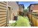 A tidy backyard with artificial turf, bordered by a wooden fence and rock garden, alongside home exterior at 3450 Valentia St, Denver, CO 80238