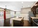 Open kitchen with an island, stainless steel appliances, dark cabinetry, and hardwood floors at 3450 Valentia St, Denver, CO 80238