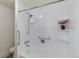 Clean, white tiled bathtub and shower combination with built-in shelving and accessibility features at 1850 Folsom St # 411, Boulder, CO 80302