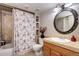 Traditional bathroom features tub with shower, vanity with round mirror, and built-in shelves at 3889 S Fraser St, Aurora, CO 80014