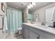 Well-lit bathroom showcasing a gray vanity with white countertop and a shower with a light blue curtain at 4581 S Kipling Cir, Denver, CO 80123