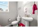 Well-lit half bathroom featuring a pedestal sink, toilet, and modern fixtures at 4581 S Kipling Cir, Denver, CO 80123