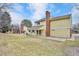 Spacious backyard with a well-maintained lawn, mature trees, and a brick chimney at 10627 Chautauga Mtn, Littleton, CO 80127