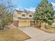 Charming two-story yellow home with a brick facade, complemented by a two-car garage and lush front yard landscaping at 10627 Chautauga Mtn, Littleton, CO 80127
