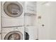 A compact laundry room featuring a stacked washer and dryer unit, accompanied by a sink and ample storage space at 10627 Chautauga Mtn, Littleton, CO 80127