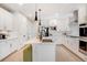 Modern kitchen with stainless appliances, white cabinetry, an island with seating, and hardwood flooring is on display at 8437 Mount Kataka Loop, Littleton, CO 80125