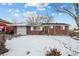 Brick ranch home with attached garage, snowy yard, and covered carport at 8261 Delaware St, Denver, CO 80221