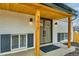 Close up of covered front porch with wood detail and freshly painted white brick at 7017 W 62Nd Pl, Arvada, CO 80003