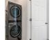 Modern laundry area showcasing stacked front load washer and dryer in a neutral tone next to a white door at 23527 E 5Th Pl, Aurora, CO 80018