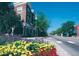 Charming street view with colorful flowers, mature trees, and building exterior on a clear day at 5201 S Fox St # 102, Littleton, CO 80120