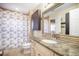 This bathroom features a granite countertop, decorative mirror, and shower with a floral curtain at 15691 E Atlantic Cir, Aurora, CO 80013
