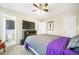 Comfortable bedroom features a ceiling fan, television, ensuite bath, and gray and purple bedding at 15691 E Atlantic Cir, Aurora, CO 80013
