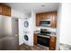 Efficient kitchen with stainless steel appliances, wood cabinets, and stacked washer/dryer at 4087 S Clarkson S St, Englewood, CO 80113