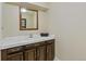 Powder room features dark wood vanity with white countertop and framed mirror at 7492 W Cedar Cir, Lakewood, CO 80226