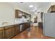 Well-lit kitchen featuring stainless steel appliances, dark cabinetry, and tile backsplash with wood floors at 7492 W Cedar Cir, Lakewood, CO 80226