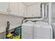 Laundry room with white washer and dryer and white storage cabinets above; vacuum cleaner at 7492 W Cedar Cir, Lakewood, CO 80226