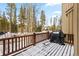 Snowy deck with a grill and wood railing, offering a peaceful view of the surrounding trees at 293 Settlers Dr, Breckenridge, CO 80424