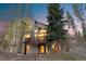 Multi-story home exterior showcasing a deck, large windows, and beautiful surrounding trees under a twilight sky at 293 Settlers Dr, Breckenridge, CO 80424