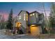 Charming home exterior featuring a garage, stone accents, and a well-lit entrance, set against a twilight sky at 293 Settlers Dr, Breckenridge, CO 80424