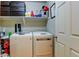 Laundry room with a side-by-side washer and dryer, storage shelves, and a white door at 1995 E 166Th Ave, Thornton, CO 80602