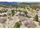 A beautiful, elevated aerial view of a house with a separate garage surrounded by mature trees at 18750 Spring Valley Rd, Monument, CO 80132
