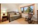 Cozy bedroom with carpeted floors and a large window looking out to trees and greenery at 18750 Spring Valley Rd, Monument, CO 80132