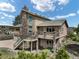 View of home featuring an elevated deck with a stairway, stone accents and nicely landscaped surroundings at 18750 Spring Valley Rd, Monument, CO 80132