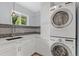 Efficient laundry room with washer, dryer, sink, gray tile backsplash and ample counter space at 2717 S Langley Ct, Denver, CO 80210