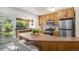 Well-lit kitchen featuring wooden cabinets, stainless steel appliances, and a breakfast bar with chairs at 14797 E Temple Dr, Aurora, CO 80015