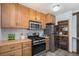 A kitchen with stainless steel appliances and light wood cabinets and an open shelf at 14797 E Temple Dr, Aurora, CO 80015