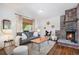 Bright living room featuring a brick fireplace, hardwood floors, neutral furniture, and natural light at 14797 E Temple Dr, Aurora, CO 80015