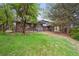 A home features a spacious backyard with a patio, lush green lawn, mature trees, and second story deck at 11351 Quivas Way, Denver, CO 80234