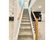 Carpeted staircase with wood handrail and black metal balusters, leading up to a white door at 8873 Princeton St, Westminster, CO 80031