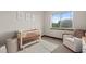 Bedroom with a crib, white chair, a window view, and three floral pictures on the wall at 2794 Heron Lakes Pkwy, Berthoud, CO 80513
