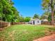 Large fenced back yard features mature trees, a storage building, and green grass at 5152 Bryant St, Denver, CO 80221