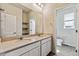 Bathroom featuring double vanity, large mirror, and a view into separate toilet room at 1397 Brookfield Pl, Erie, CO 80026