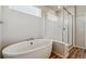 Bright bathroom featuring a modern soaking tub, glass enclosed shower, and wood look tile floors at 1397 Brookfield Pl, Erie, CO 80026
