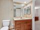 Bathroom featuring a wood vanity with sink, mirror, toilet, and wall with vertical striped wallpaper at 13668 Plaster Cir, Broomfield, CO 80023