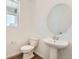 Contemporary bathroom with a pedestal sink, a toilet, and a large oval mirror at 10984 Snowdon St, Parker, CO 80134