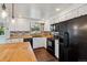 The kitchen features white cabinets, black appliances, butcher block countertops, and brick backsplash at 13472 W Dakota Ave, Lakewood, CO 80228
