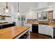 This kitchen features white cabinets with a brick backsplash, butcher block countertops and stainless steel appliances at 13472 W Dakota Ave, Lakewood, CO 80228