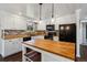 The kitchen features white cabinets, black appliances, butcher block countertops, brick backsplash and a center island at 13472 W Dakota Ave, Lakewood, CO 80228