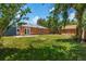 Large, grassy backyard with mature trees and a brick home, creating a private outdoor oasis at 9320 Fir Dr, Thornton, CO 80229
