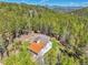 Aerial view of home with orange roof surrounded by lush green trees and mountains at 9092 Gray Ln, Conifer, CO 80433