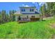 Back of a two-story home with a wooden deck overlooking a large green lawn at 9092 Gray Ln, Conifer, CO 80433