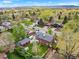 Expansive aerial view of a neighborhood with a brick home, green lawn, mature trees, and mountain views at 2210 Miller St, Lakewood, CO 80215