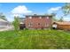 Large backyard showcasing a lush lawn, mature trees, and a red brick home with plenty of natural light at 2210 Miller St, Lakewood, CO 80215
