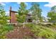 Charming brick two-story home featuring a covered front porch, landscaped garden, and mature trees at 2210 Miller St, Lakewood, CO 80215