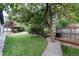 Expansive backyard with artificial grass, dining area, gravel path, and mature trees for privacy at 1392 W Caley Ave, Littleton, CO 80120