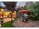 Well-maintained backyard featuring stone patio with dining set, artificial grass, and lush landscaping at 1392 W Caley Ave, Littleton, CO 80120